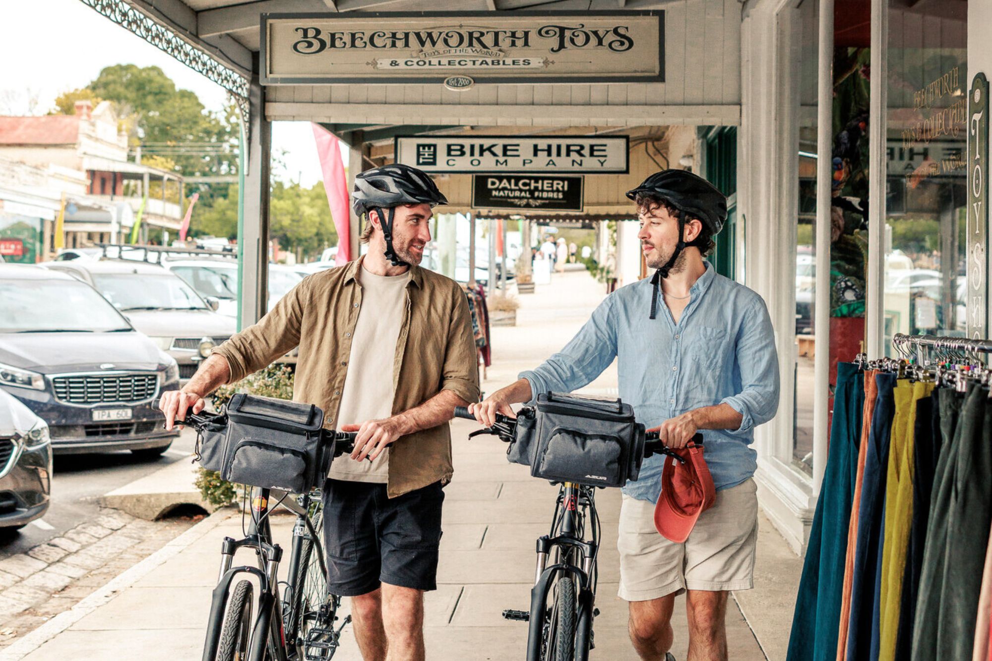 Two recreational cyclists pushing their bikes through the streets of Beechworth.