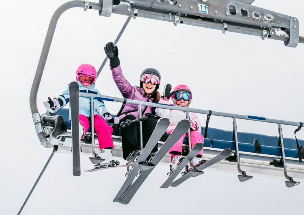 Mother and two young children riding the Bourke Street Express chairlift at Mt Buller