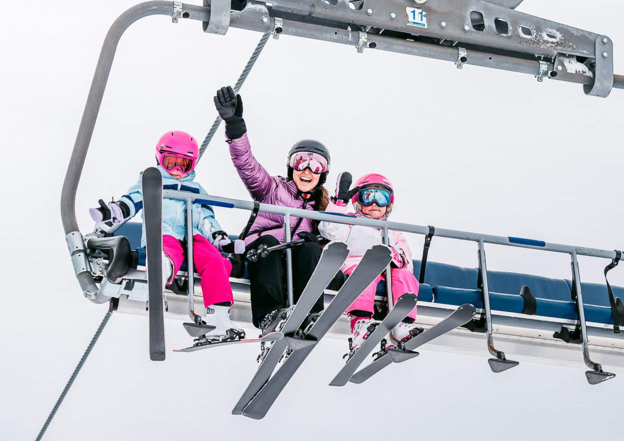 Mother and two young children riding the Bourke Street Express chairlift at Mt Buller