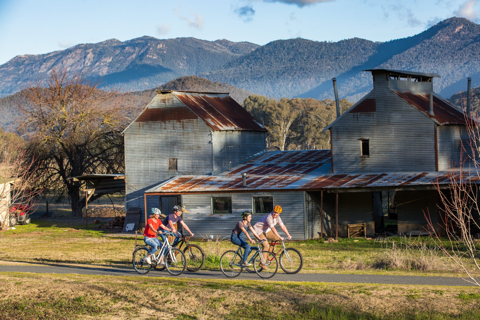 Group of cyclists riding past the Myrtleford tobacco kilns on the Murray to Mountains Rail Trail