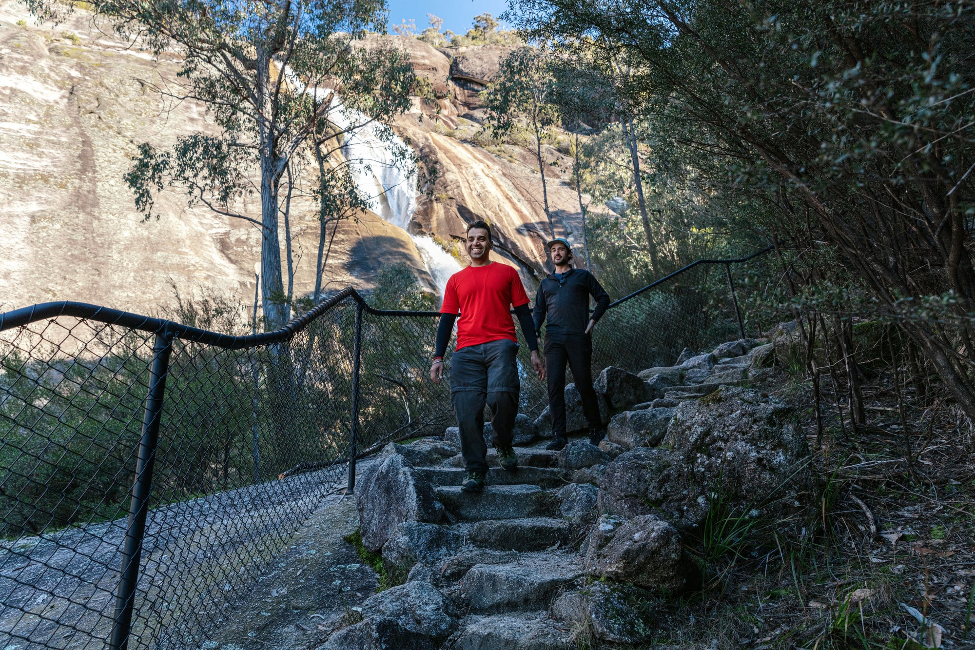 Two people smiling and walking past Eurobin Falls on Mount Buffalo