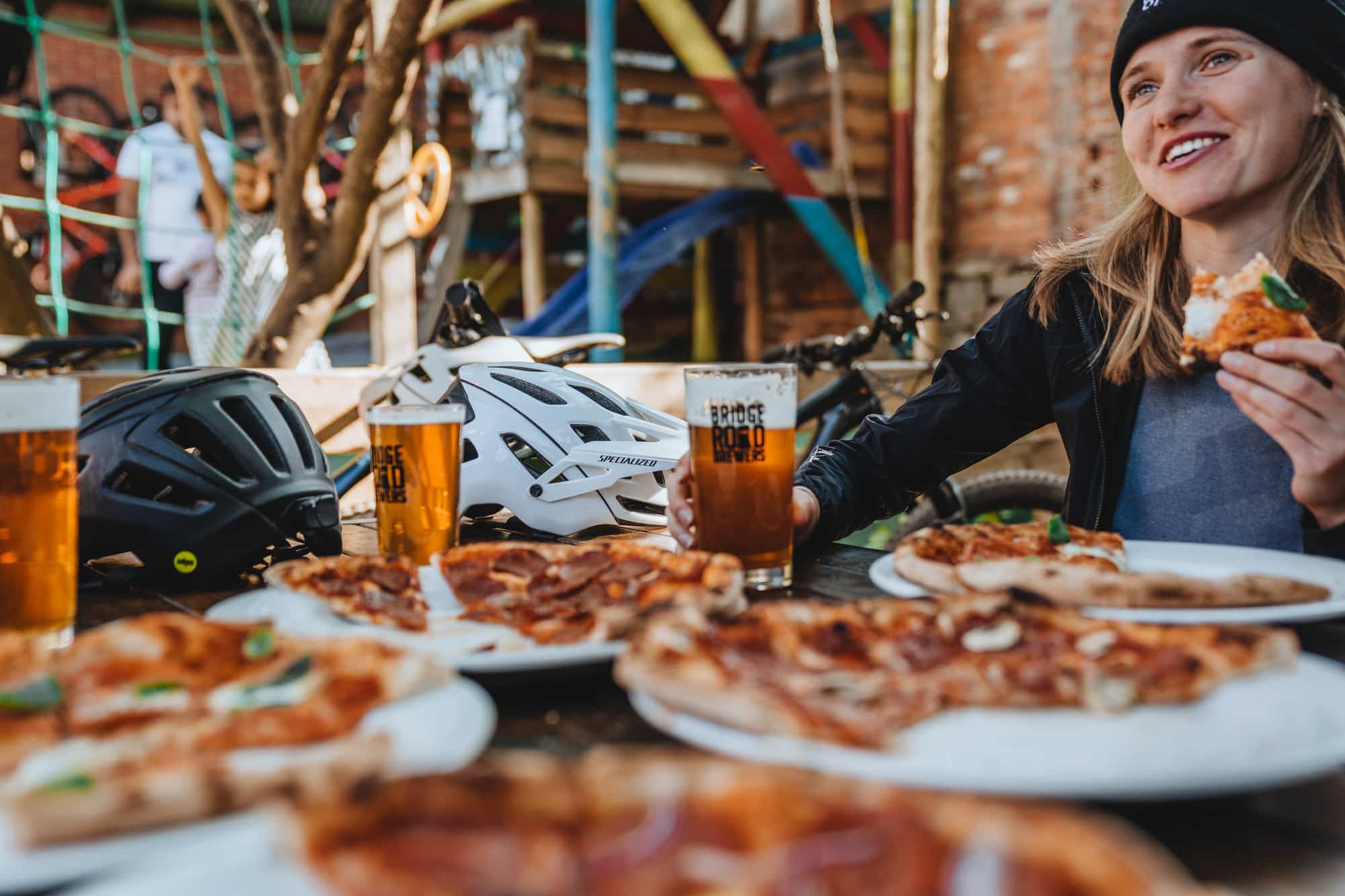 A cyclist enjoying pizza and beer at Bridge Road Brewers with pizzas in the foreground