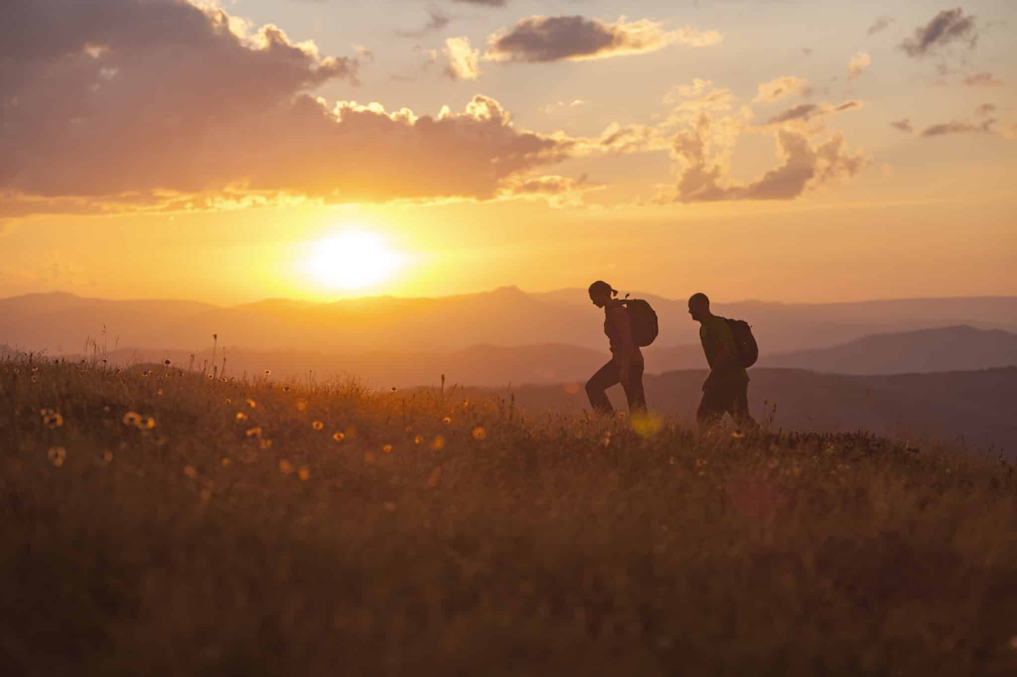 Two people bushwalking at sunrise on the Razorback, Mt Hotham