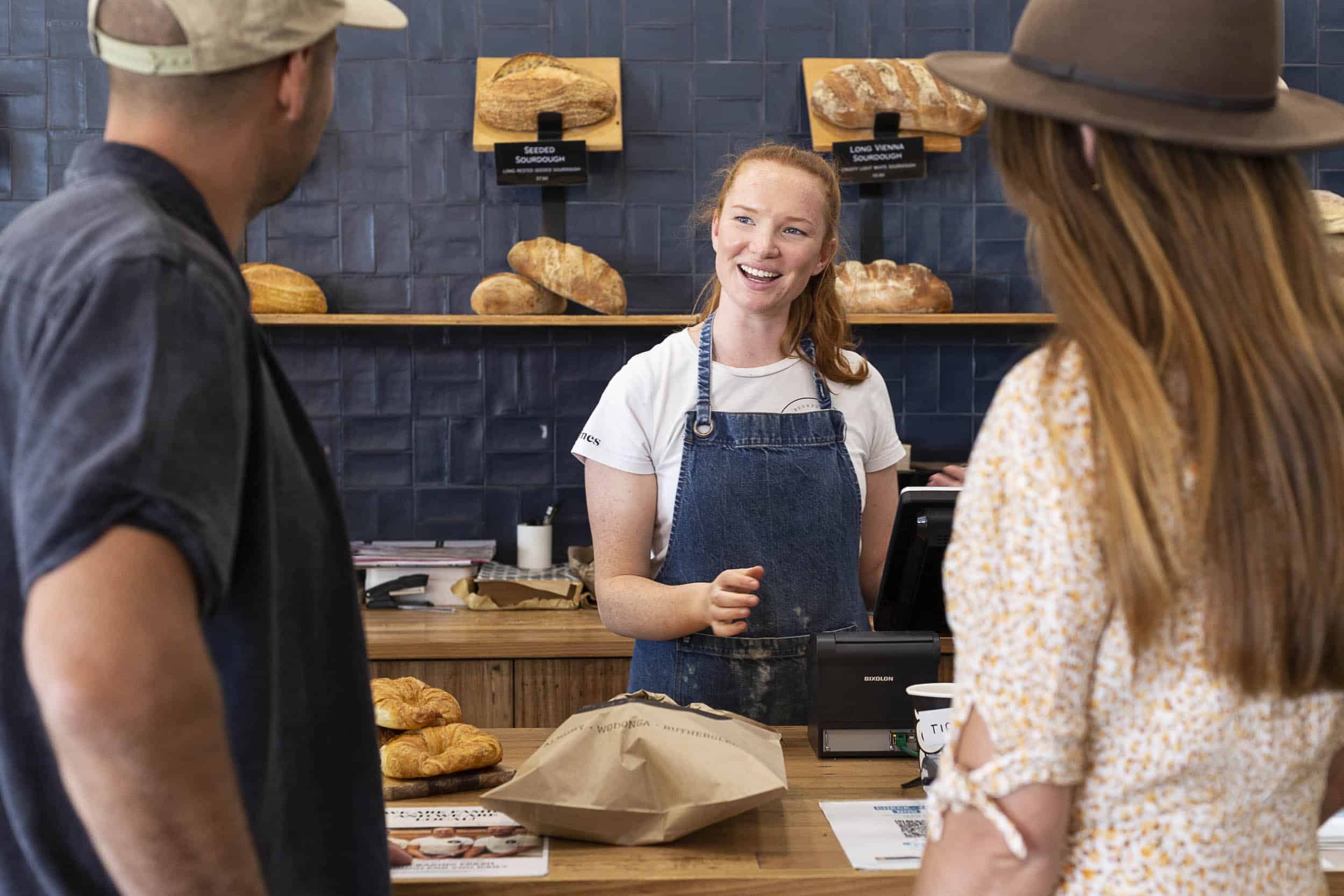 A couple being served by a smiling young woman at Valentines Bakery, Rutherglen