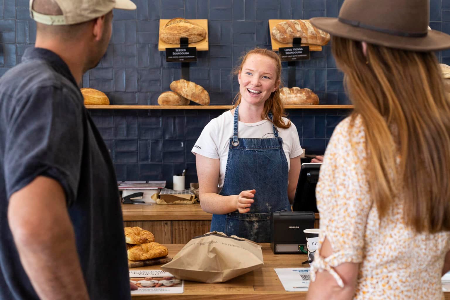 couple being served by a smiling young woman at Valentines Bakery