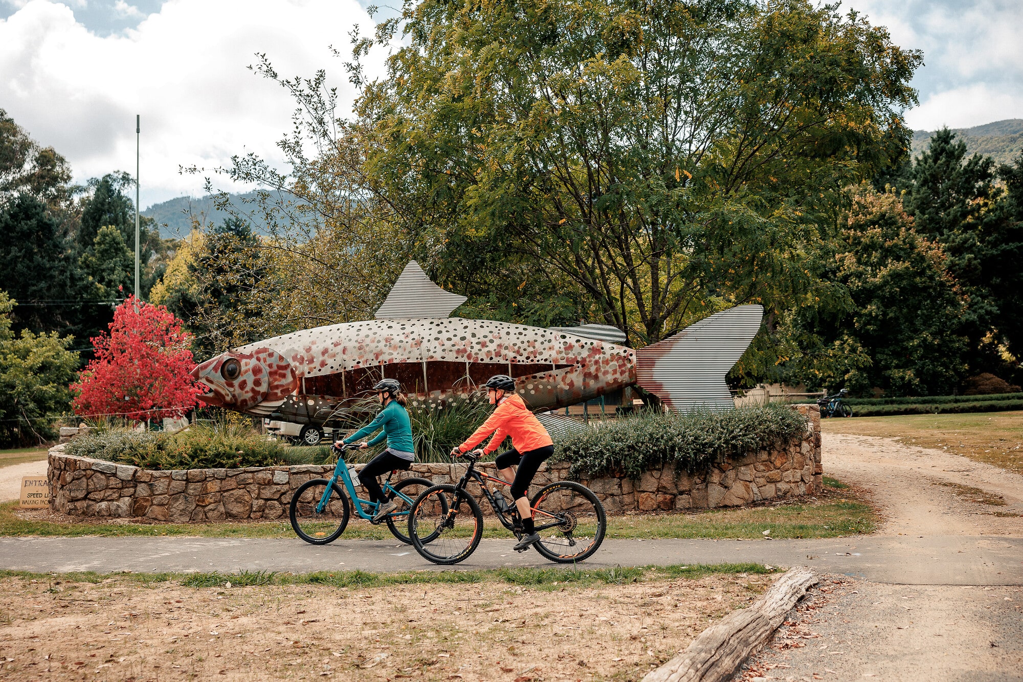 Two cyclists riding past the salmon and trout farm on the Great Valley Trail that stretches between Bright and Harrietville