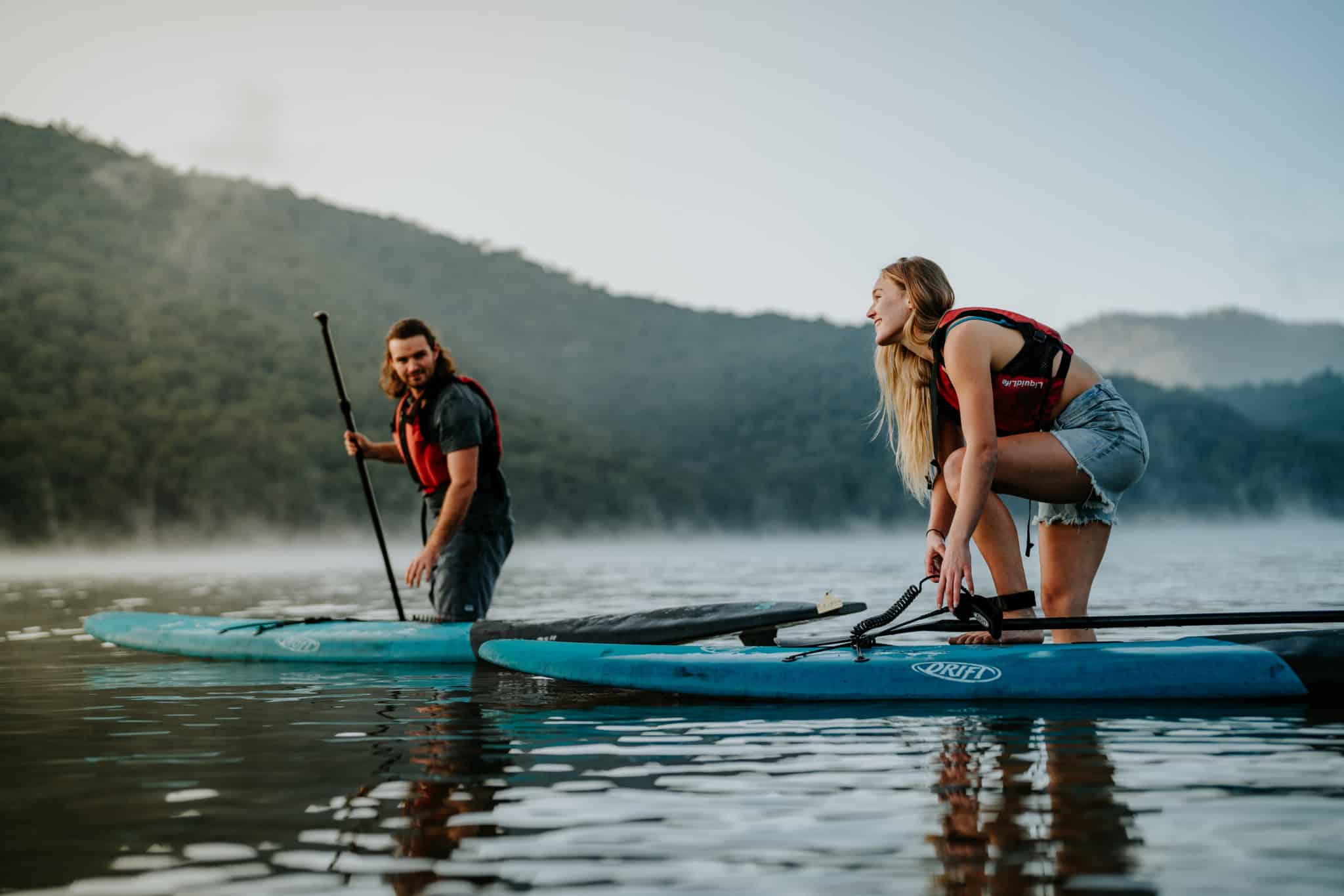 A young couple stand up paddle boarding at Lake William Hovell