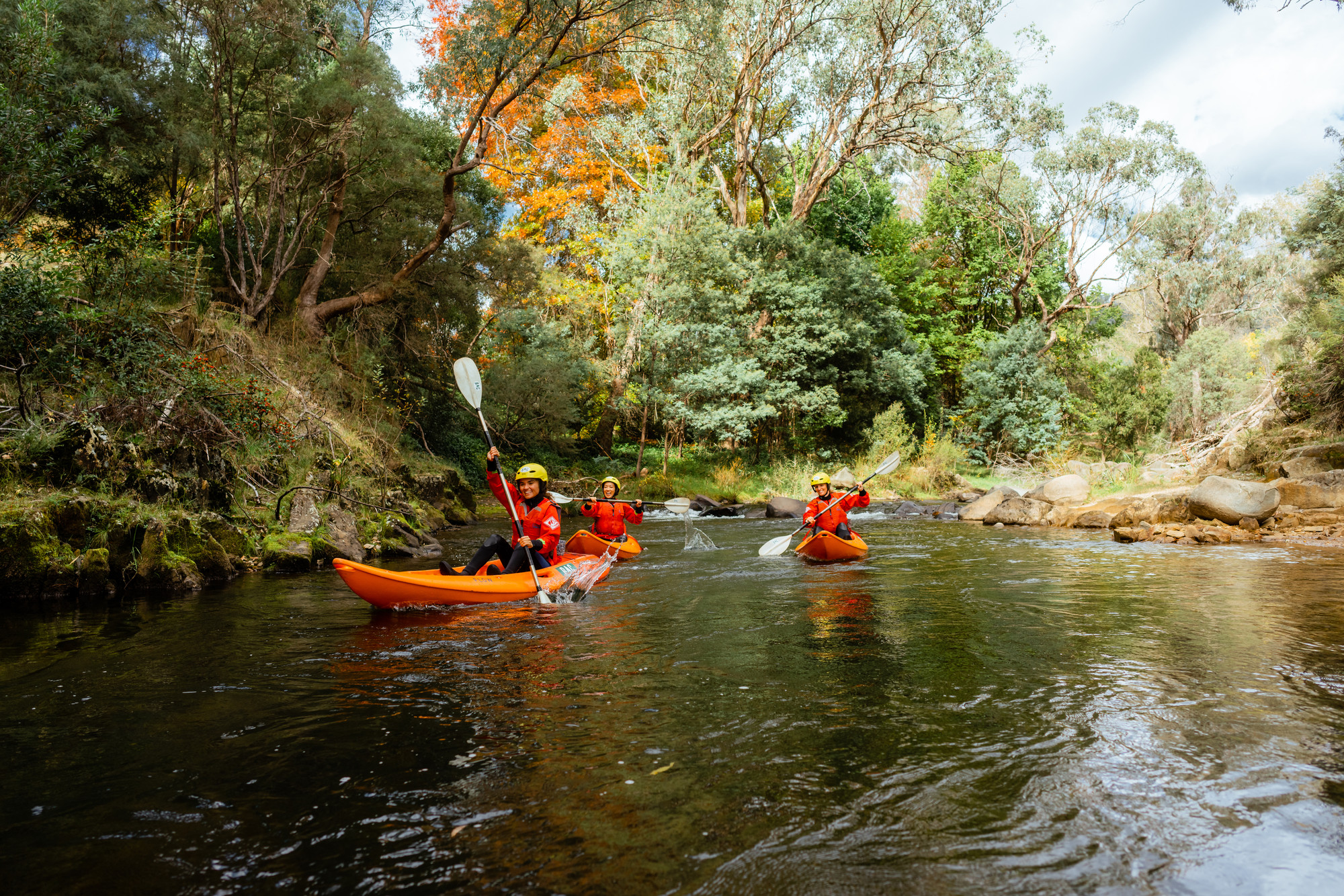 Three people kayaking on the Ovens River in Bright in Autumn