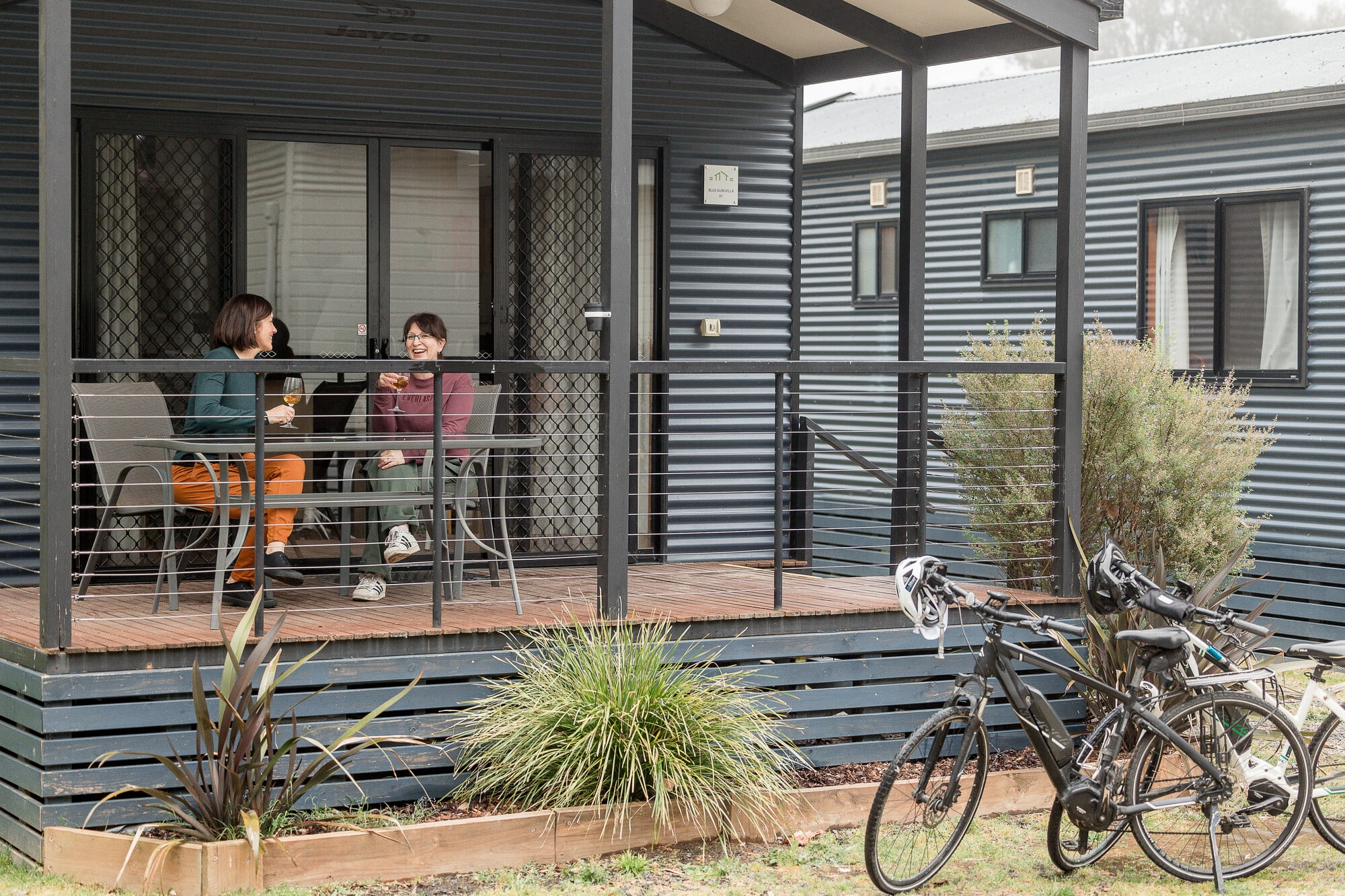Two cyclists relaxing on the balcony at Yea Riverside Caravan Park.