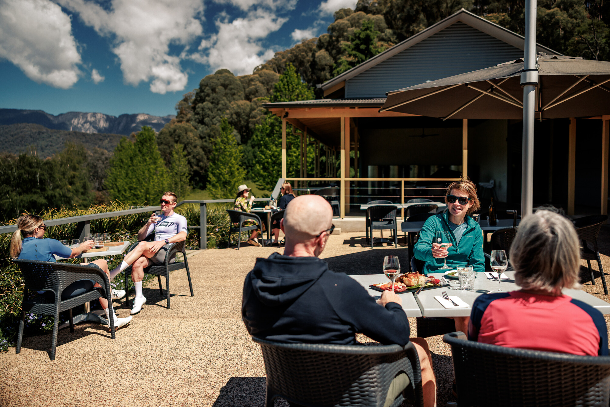 A group of cyclists relaxing at Ringer Reef Winery with views of Mount Buffalo in the background.