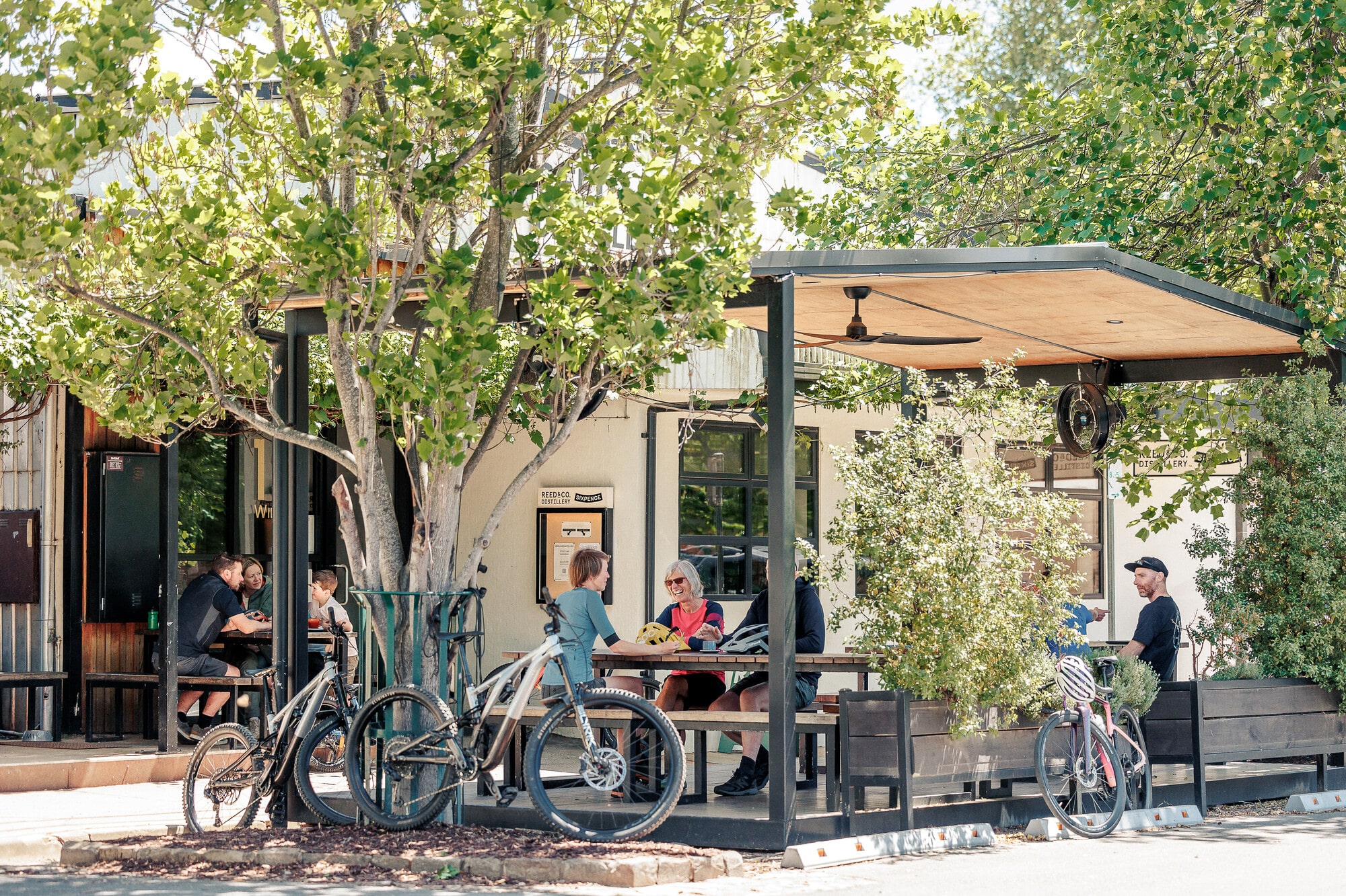Group of cyclists sitting outside enjoying coffee at Sixpence Coffee Roasters.