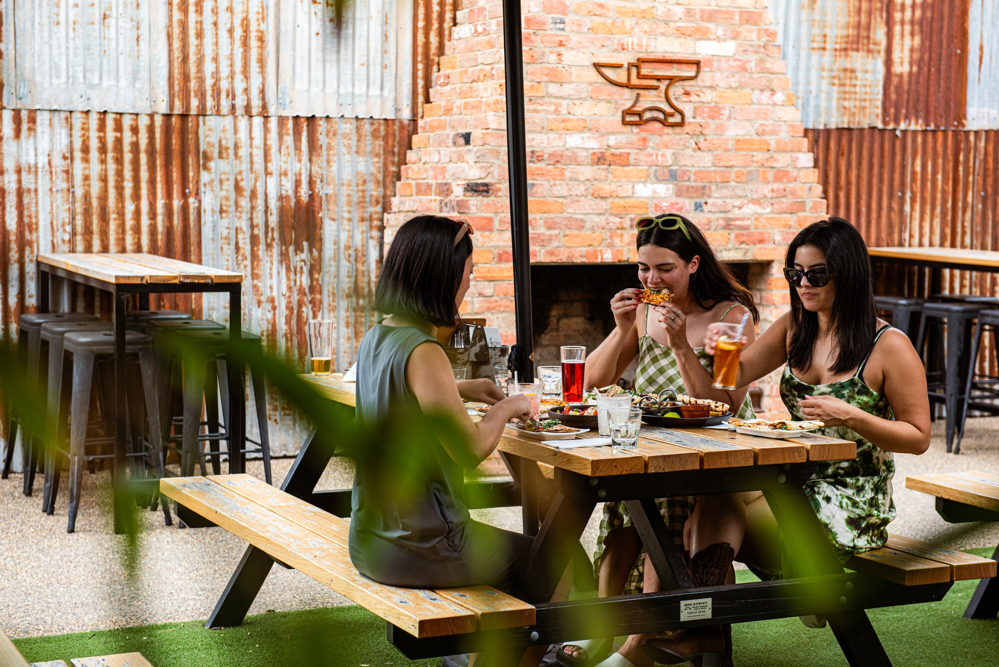 A group of people enjoying pizza and drinks at Anvil Brewing.