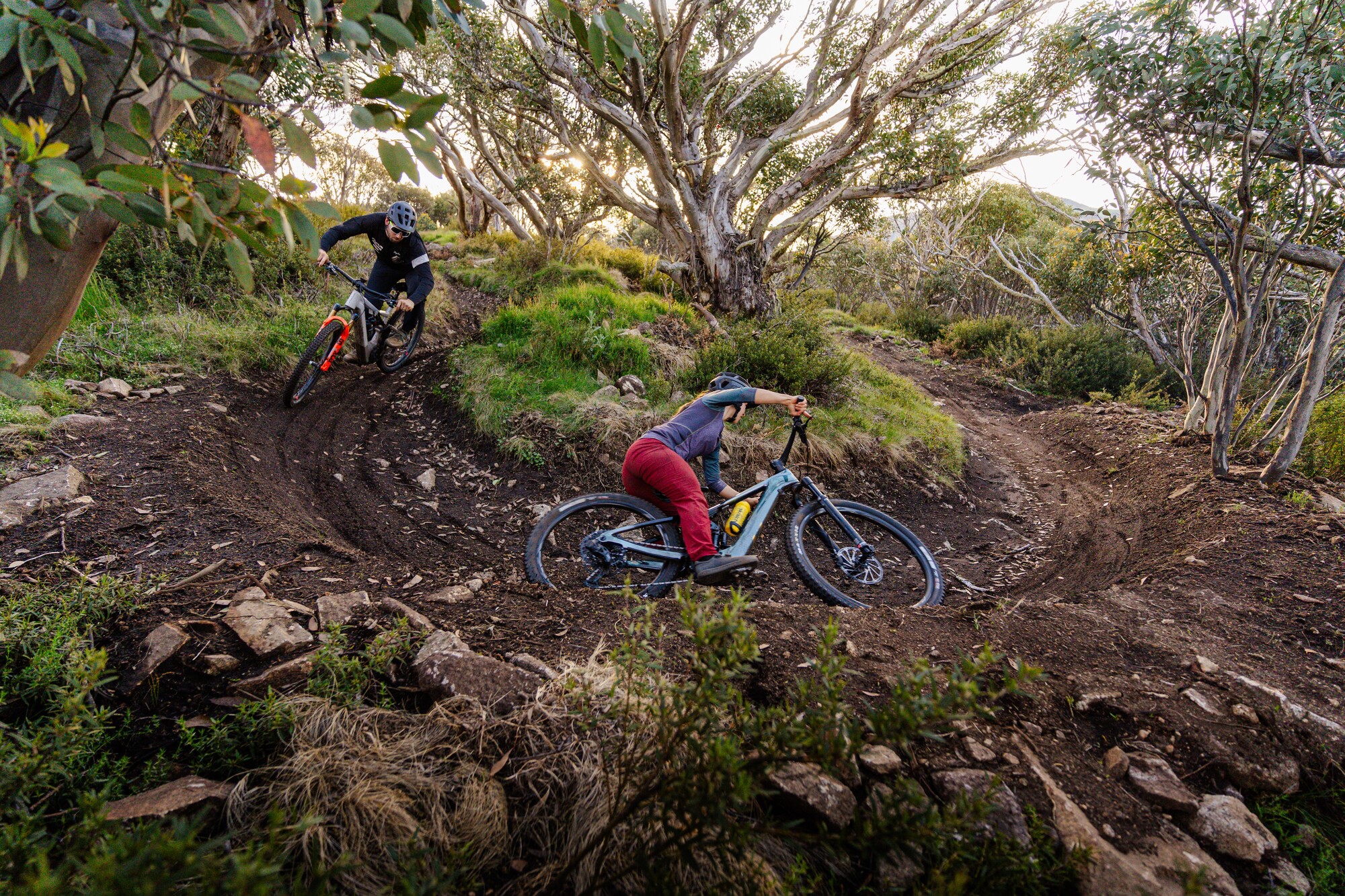 Two mountain bike riders cycling around a berm at the Mt Buller Mountain Bike Park.