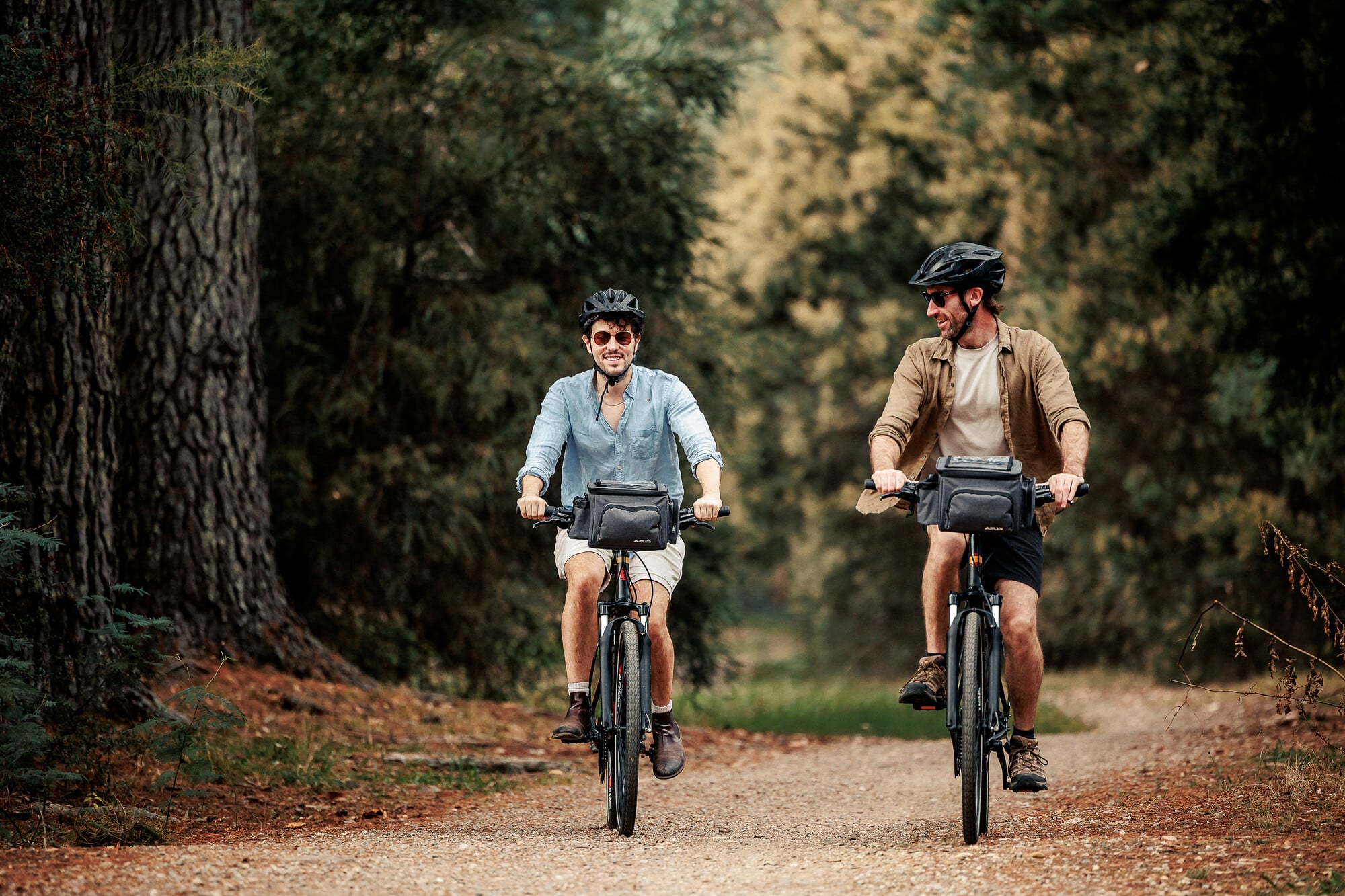 Two people riding between pine trees in the township of Beechworth on the Murray to Mountains Rail Trail