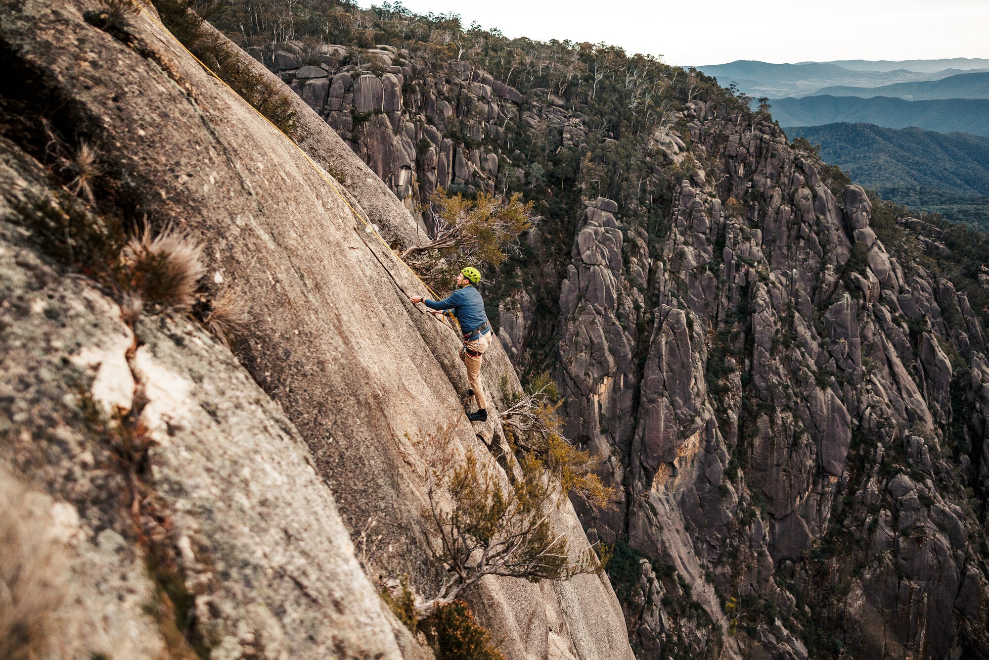 Person rock climbing on Mount Buffalo's cliffs with Adventure Guides Australia with mountain views in the background