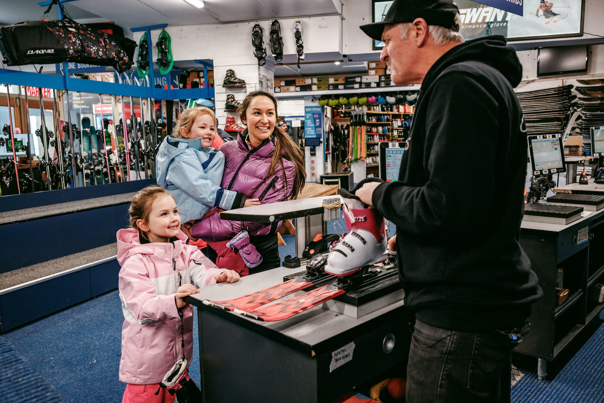 A parent and two young children hiring ski equipment from George's Ski Hire at Mt Buller.