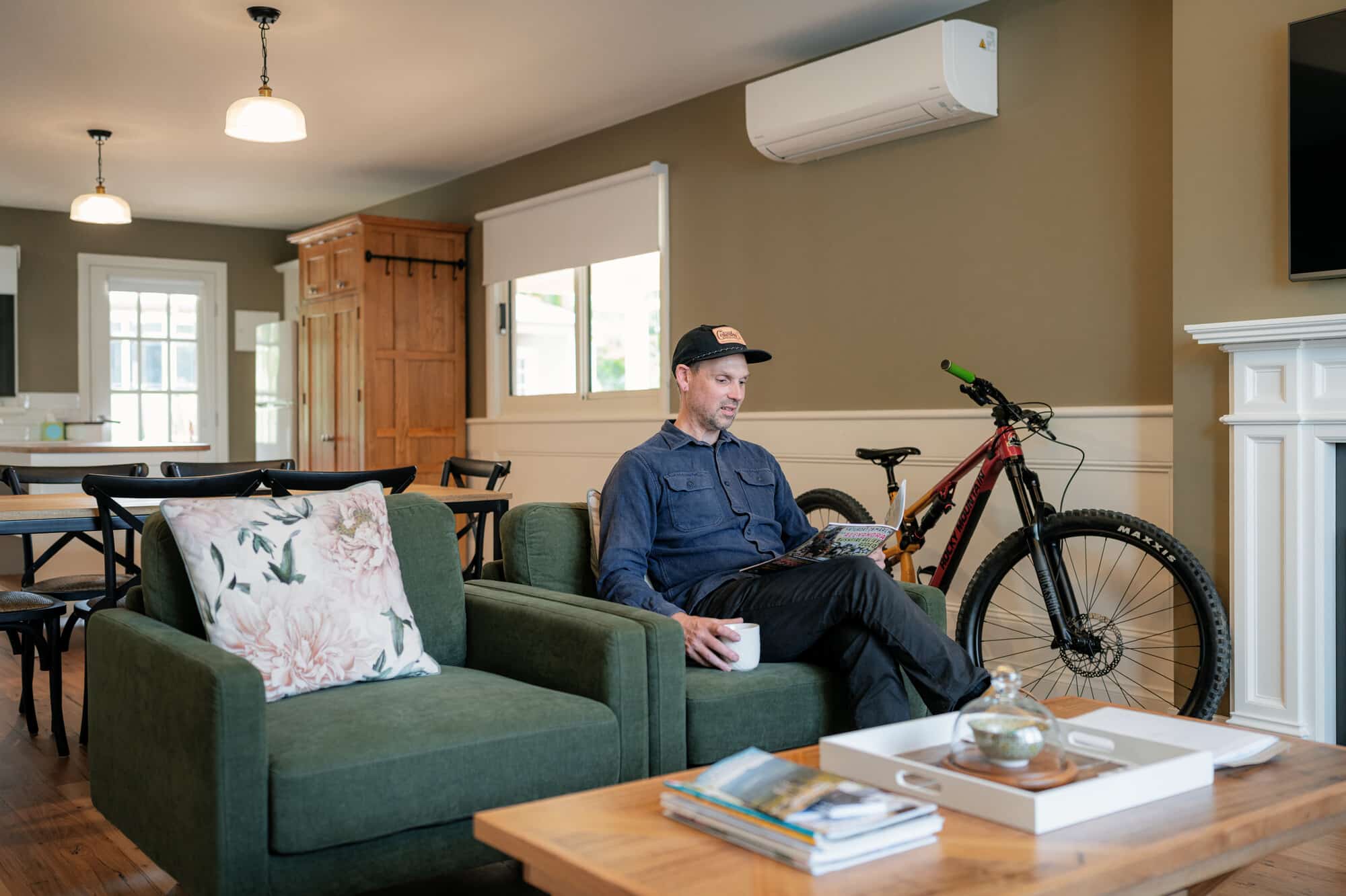 Person reading a book in Scenic Marysville's cottage with a mountain bike stored in the background.