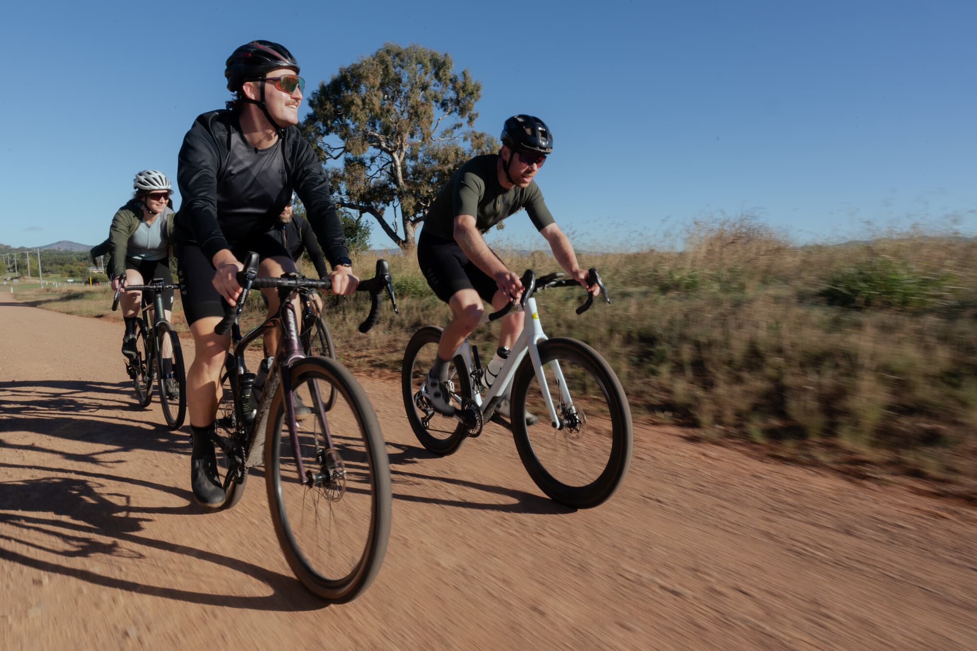 Group of gravel cyclists riding along Mansfield's gravel roads in the sunshine.