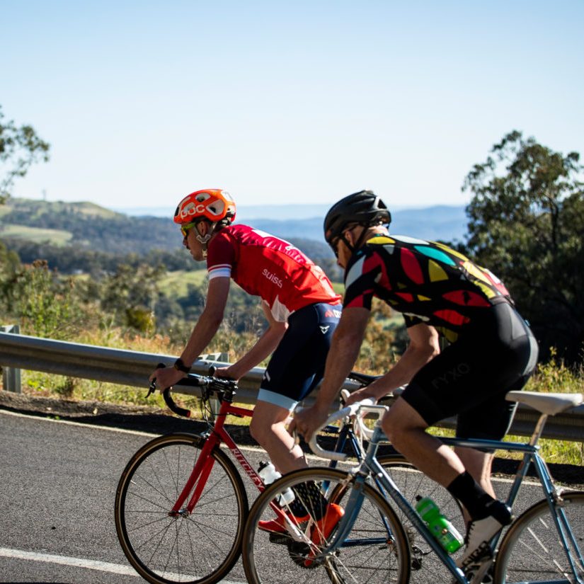 Two road cyclists riding up a hill in the King Valley