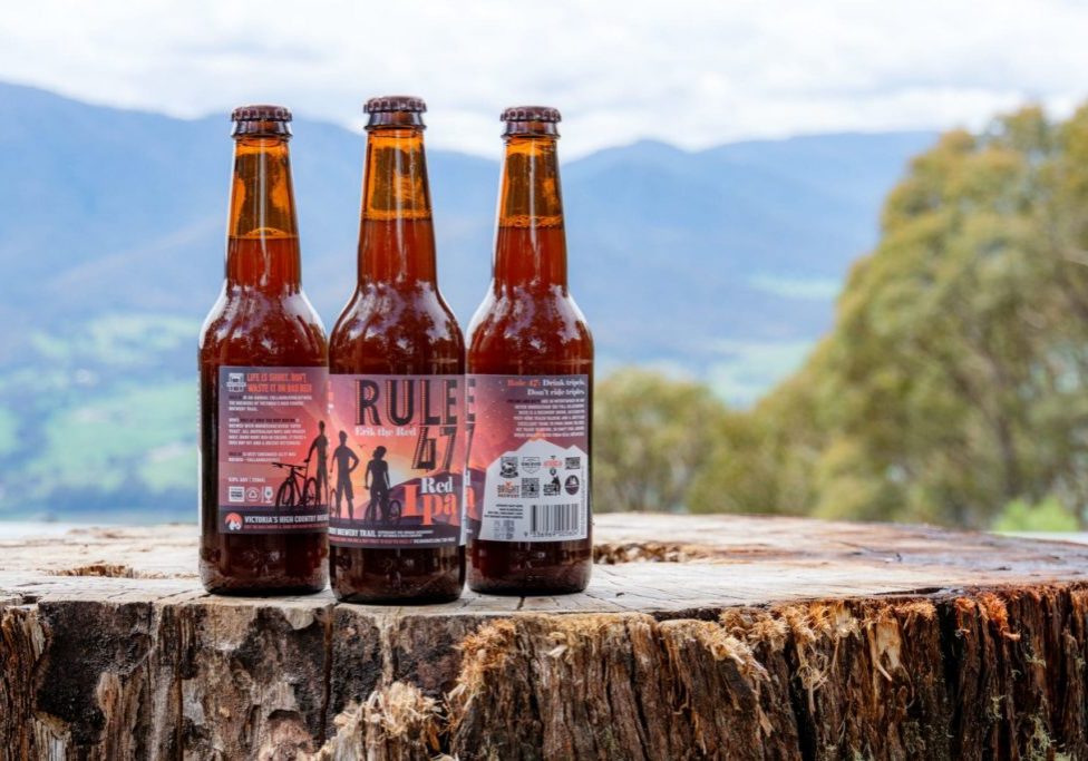 3 bottles of the Rule 47 beer with a mountain backdrop